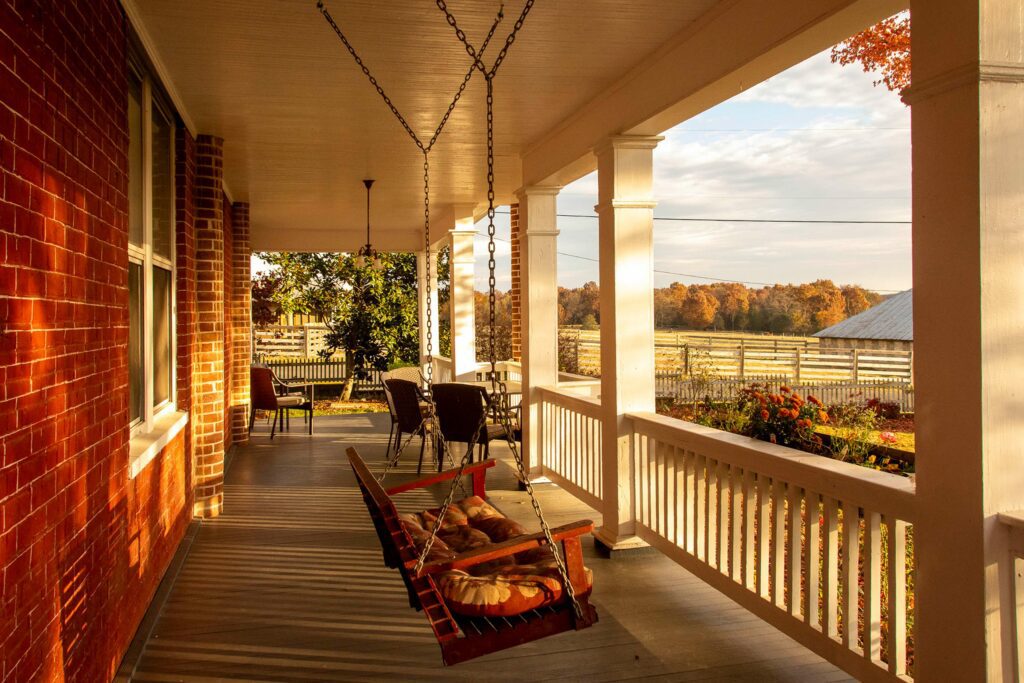 Hanging chairs on a porch. View out to surrounding farms fall colors.